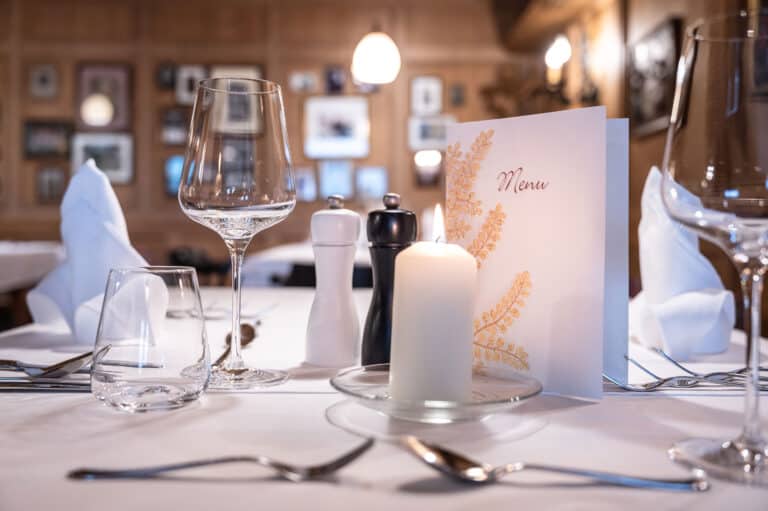 Edler Restauranttisch mit Kerzen, Weingläsern und Menükarte für Special Events.